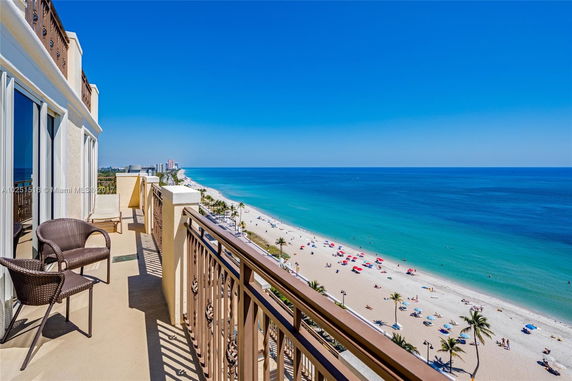 Panoramic view from a balcony overlooking a beach and ocean.