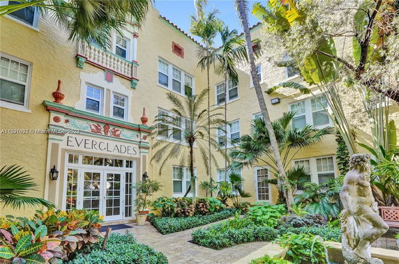 Front view of a multistory apartment building named Everglades with decorative architectural elements and lush greenery.