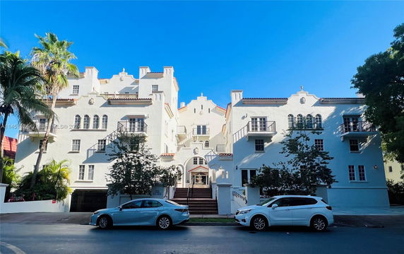 Front view of a multi-story residential building with balconies and an arched entrance.