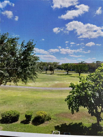 Outdoor view of a landscaped area with trees and grass under a clear blue sky.
