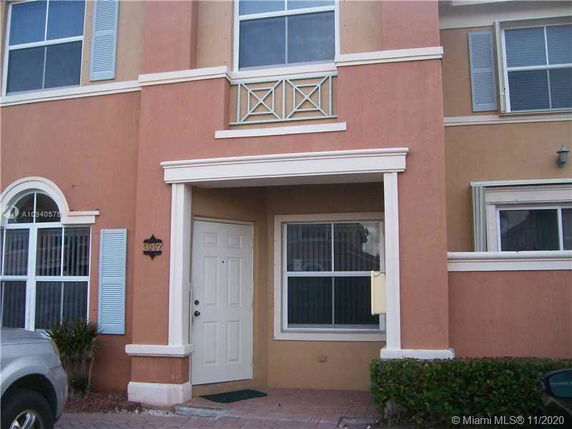 Front view of a two-story house with a beige and peach facade, featuring white trim around windows and doors.