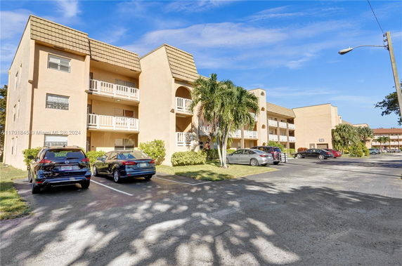 Front view of a multi-story apartment building with a parking area.