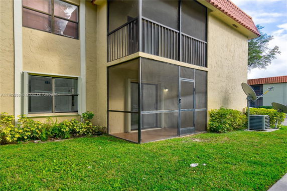Front view of a two-story building with screened porch and tiled roof.