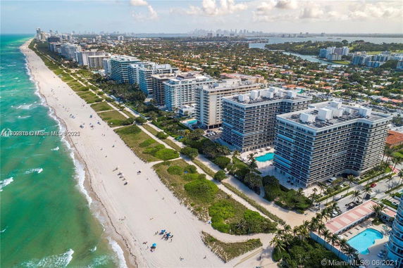 Aerial view of beachfront buildings surrounded by greenery and ocean.