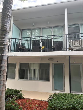 Front view of a two-story building with a balcony and ground floor entry.