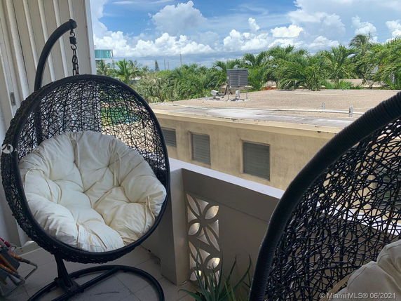 Rooftop with a view of palm trees and hanging chairs.