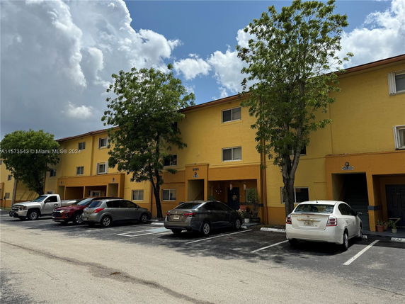 Front view of a multi-story residential building with parking spaces in front.