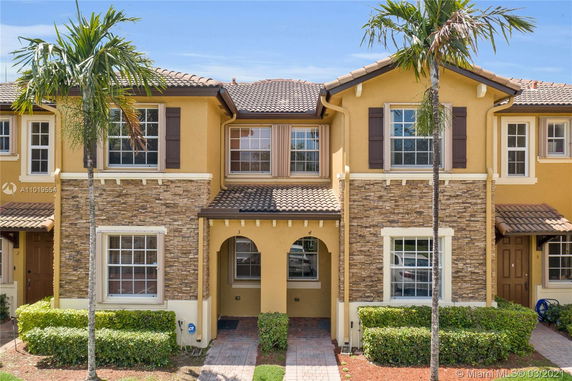 Front view of a two-story townhouse with stone accents and a tiled roof.