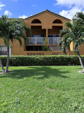 Front view of a two-story house with a balcony and arched design elements.