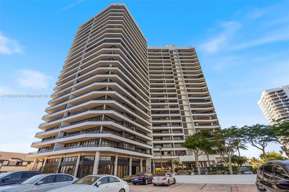 Front view of a tall, multi-story apartment building with balconies.