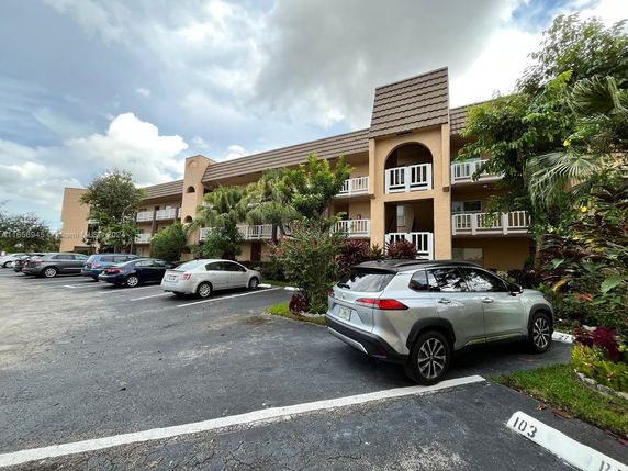 Outdoor parking area in front of a three-story residential building with balconies.