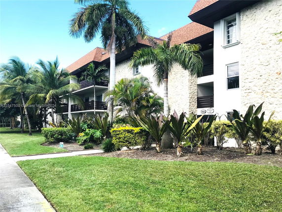 Front view of a multi-story building with palm trees and balconies.