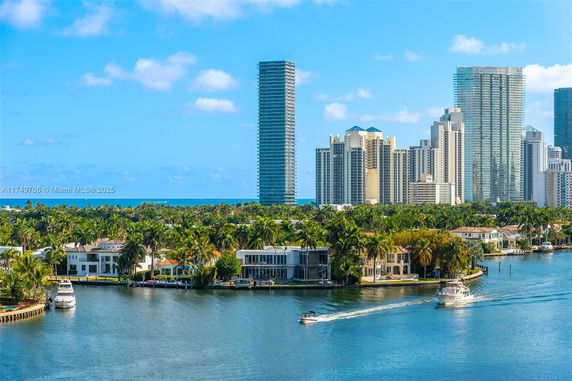 Skyline view of high-rise buildings and waterfront residences with boats on the water.