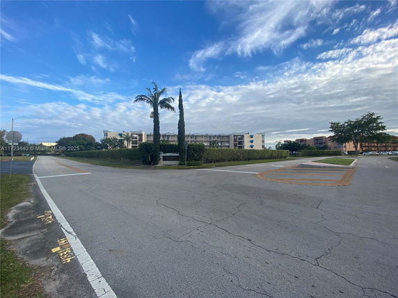 View of a multi-story building with surrounding road and vegetation.