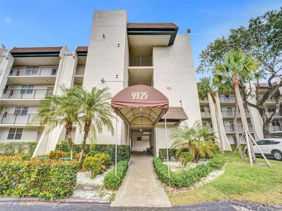 Front view of a multi-story residential building with balconies and a canopy entrance.