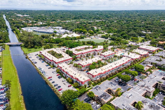 Aerial view of residential buildings with parking areas and surrounding greenery.
