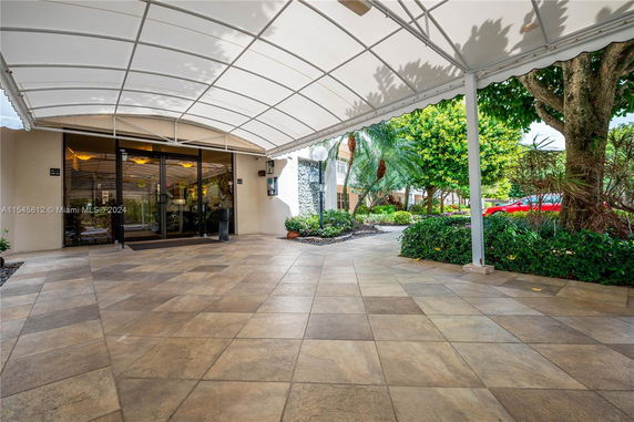 Entrance with a covered canopy leading to glass doors and surrounded by landscaping.