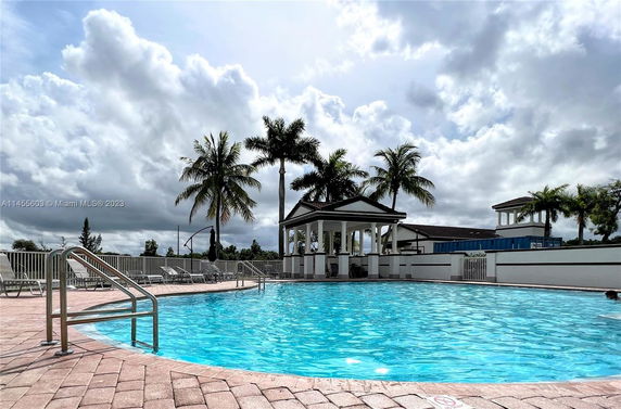 Outdoor swimming pool area with a gazebo and palm trees around.