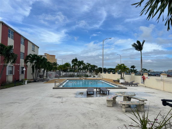 Outdoor area with a swimming pool and seating near a building.