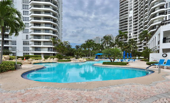 View of tall condominium buildings surrounding a swimming pool area.