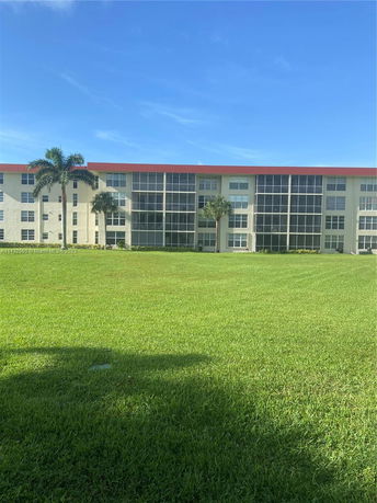 Front view of a multi-story residential building with large windows and palm trees.