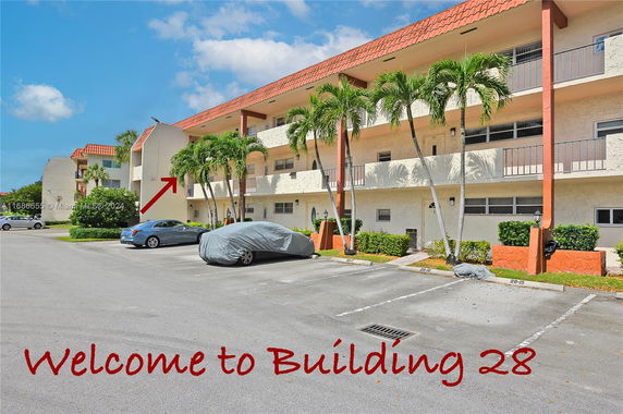 Front view of a multi-story residential building with a parking area.