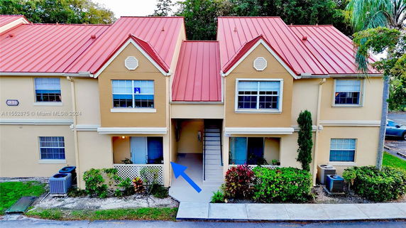Front view of a two-story building with red metal roofs and beige walls.