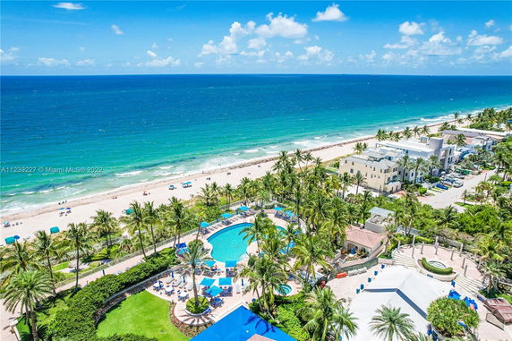 Panoramic view of a beachside area with a pool and surrounding buildings.
