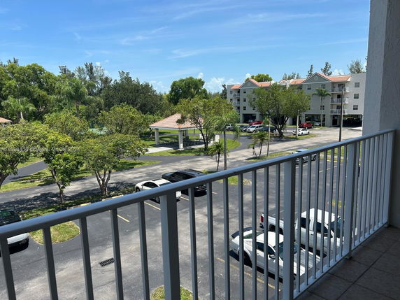 View from a balcony showing nearby buildings and parking area.