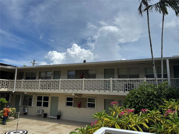Front view of a two-story apartment building with a balcony and multiple doors and windows.