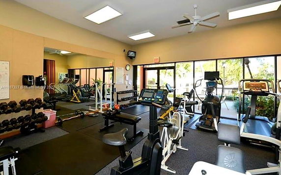 Indoor gym with exercise equipment and large windows.