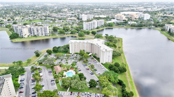 Aerial view of residential buildings surrounded by water bodies and green areas.