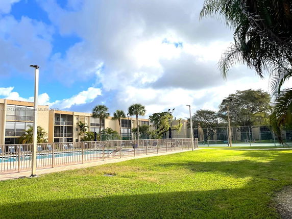 View of a building with a swimming pool and tennis court in the outdoor area.