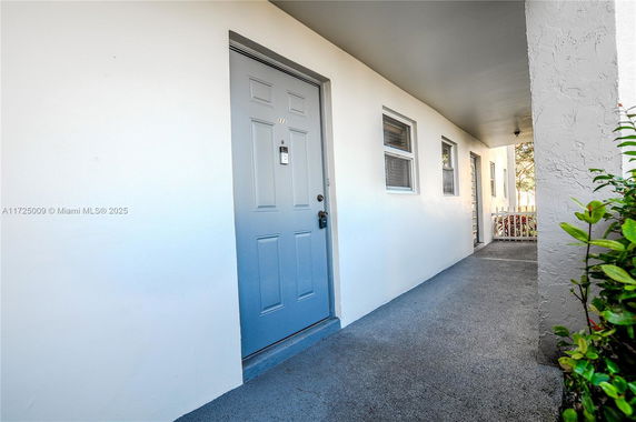 Front view of a building with a blue door and exterior walkway.