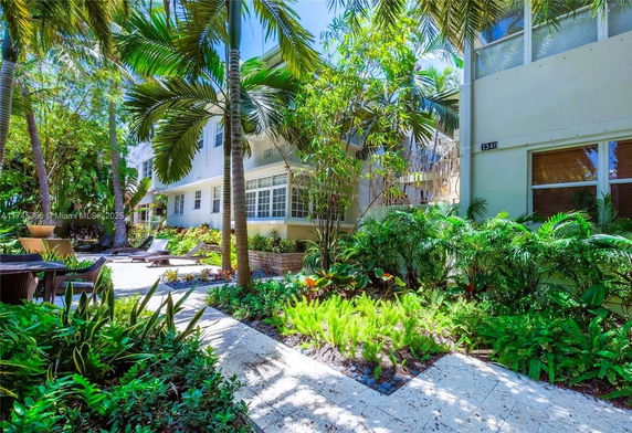 A building surrounded by lush tropical landscaping with palm trees and outdoor seating.