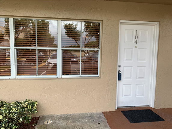 Front view of a building entrance with a white door and adjacent window.