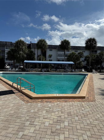 Outdoor swimming pool in front of a multi-story building.