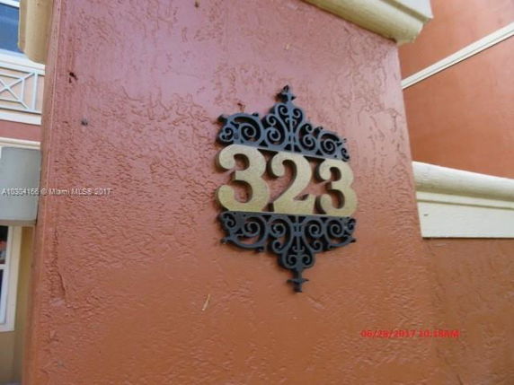 Close-up view of a building wall with the number 323 displayed on a decorative plaque.