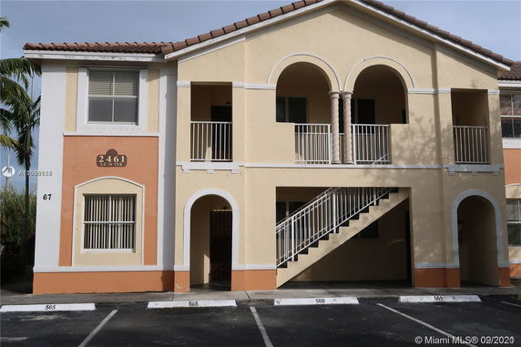 Front view of a two-story building with arched balconies and staircase.