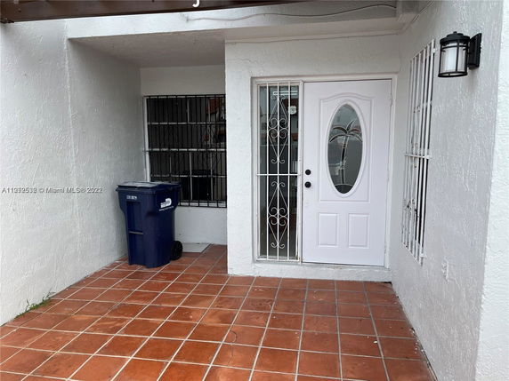 Front entrance of a house with a white door and security bars on windows.