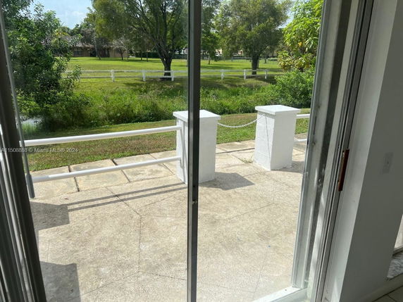 View from a building showing a grassy area with trees and a white fence.
