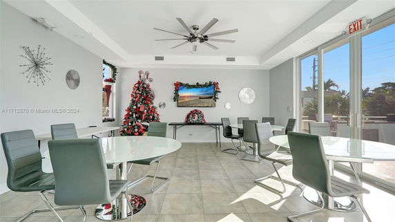Interior view of a recreational room with tables and chairs, decorated with a Christmas tree and festive ornaments.