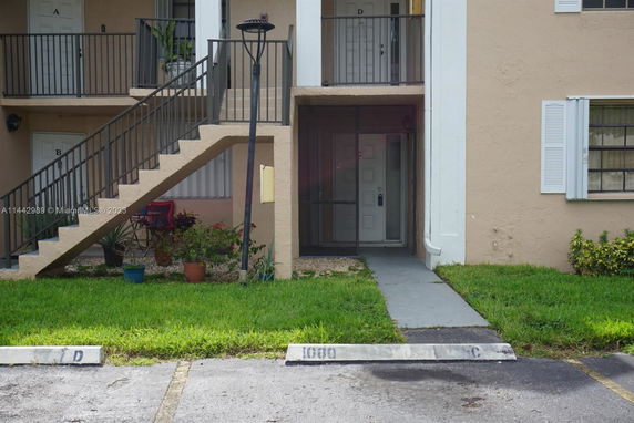 Front view of a building entrance with stairway access and parking area.