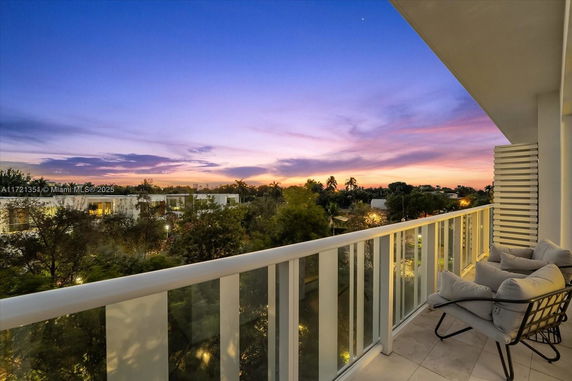 Balcony view of surrounding area during sunset with trees and buildings in the distance.