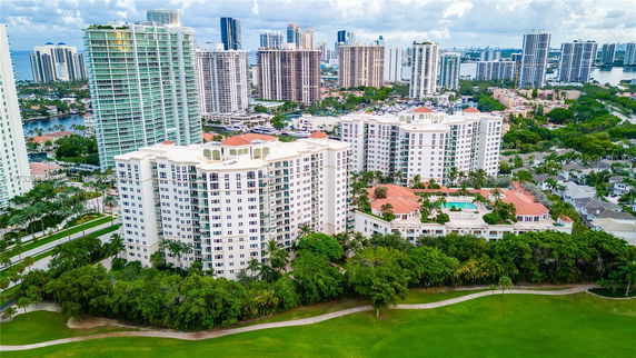 Aerial view of a cityscape with multiple high-rise buildings and greenery.