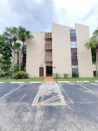 Front view of a three-story apartment building with a simple facade and staggered windows.
