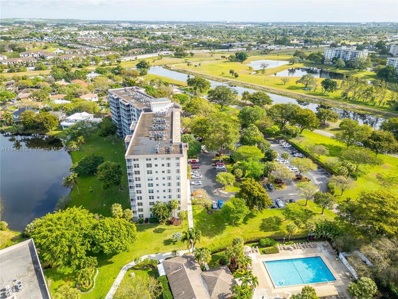 Aerial view of an apartment building surrounded by greenery and water bodies.