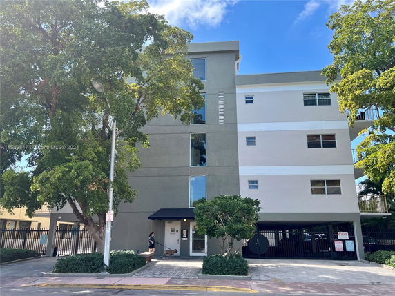 Front view of a multi-story residential building with gated parking area.