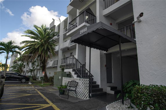 Front view of a multi-story building with a covered entrance and stairway.