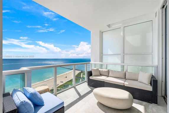 Panoramic view from a high balcony over a beach and ocean.
